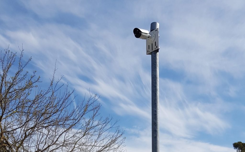 Caméra de vidéosurveillance sur poteau à l'entrée d'une résidence.